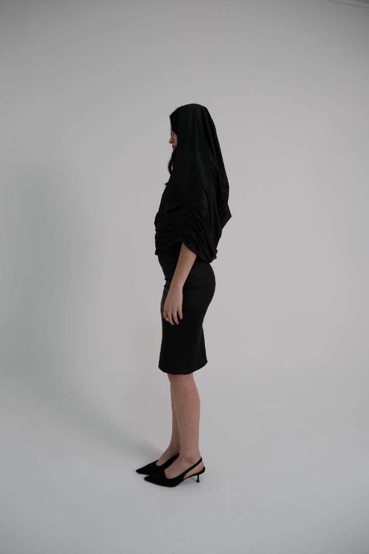 Clean side profile of sculpted black dress with stretch fit and versatile hood